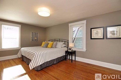 A bedroom with a bed, nightstand, and pictures on the wall.