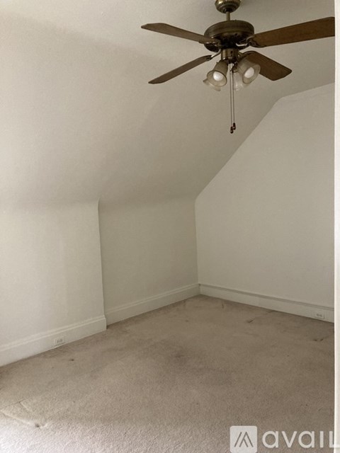 A room with a ceiling fan and carpeted floor.