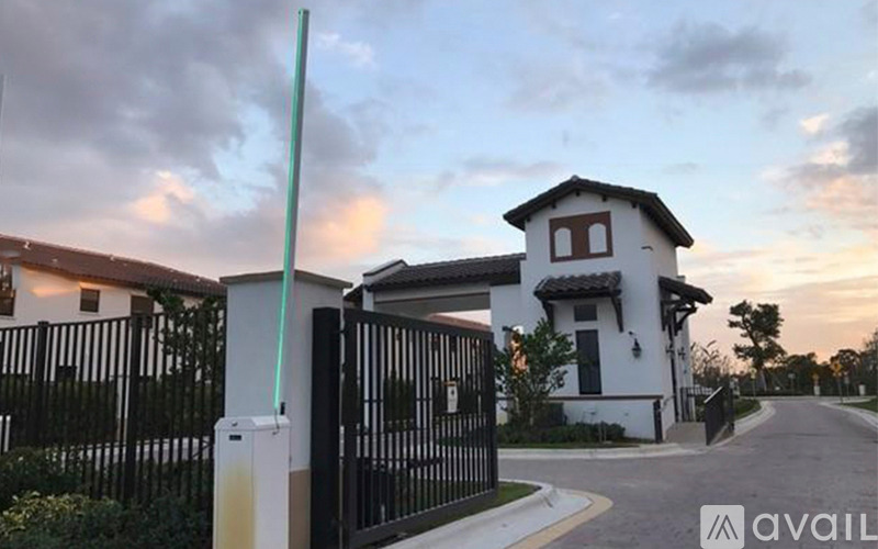 A house with a black gate and a white house in the background.