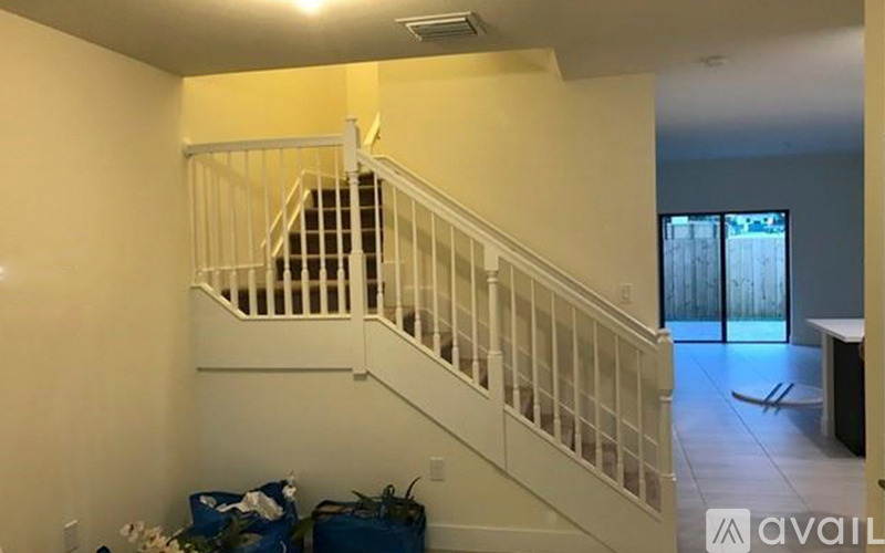 A staircase with a white railing and a blue bag on the floor.