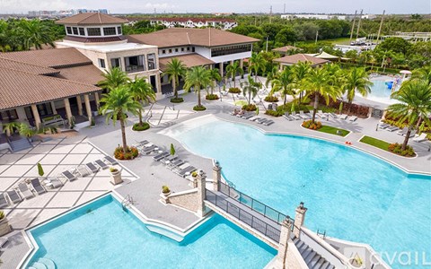 A large swimming pool surrounded by palm trees and a building.