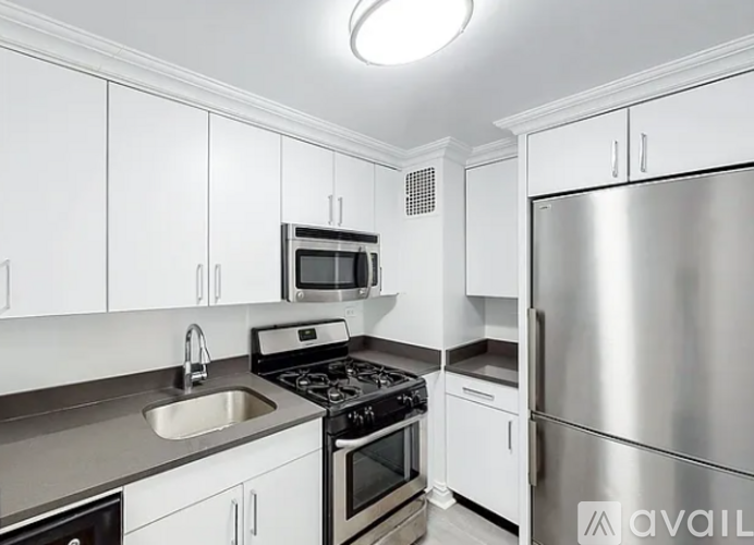A kitchen with white cabinets and a stainless steel refrigerator.