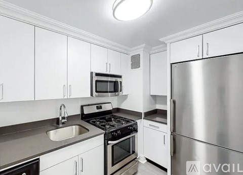 A kitchen with white cabinets and a stainless steel refrigerator.