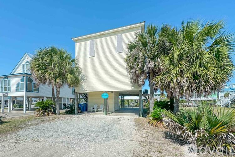 A house with a driveway and palm trees in front.