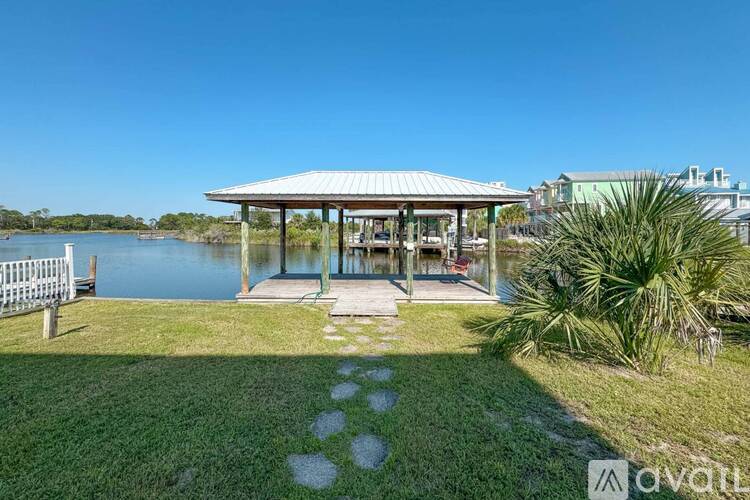 A gazebo is situated in a grassy area next to a body of water.