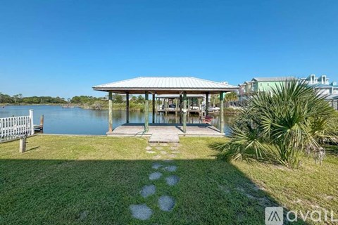 A gazebo is situated in a grassy area next to a body of water.