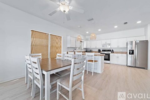 A kitchen with a table and chairs in the foreground and a refrigerator, oven, and cabinets in the background.