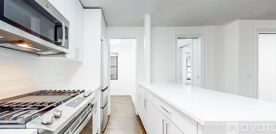 A modern kitchen with white cabinets and a stainless steel stove top.