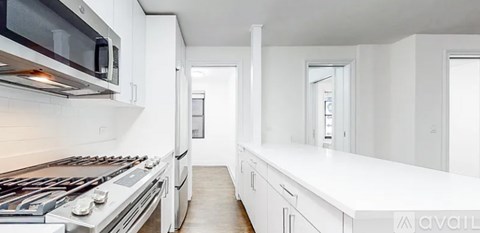 A modern kitchen with white cabinets and a stainless steel stove top.