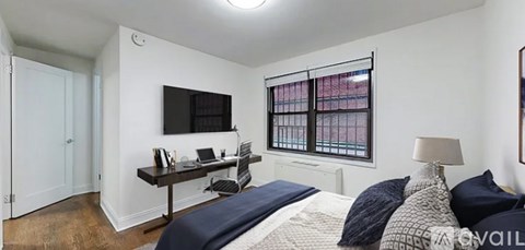 A bedroom with a bed, desk, and window.
