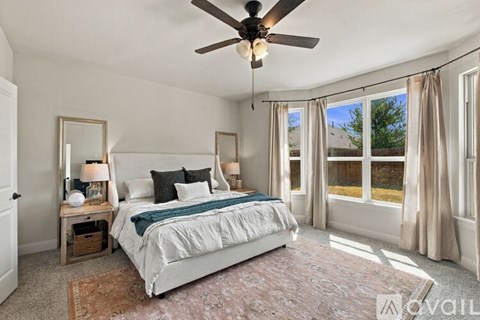 A bedroom with a large bed and a ceiling fan.