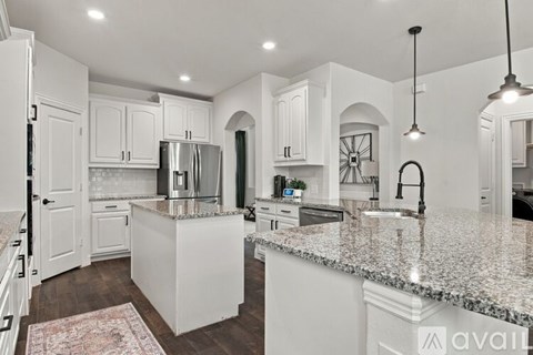 A kitchen with white cabinets and a granite countertop.