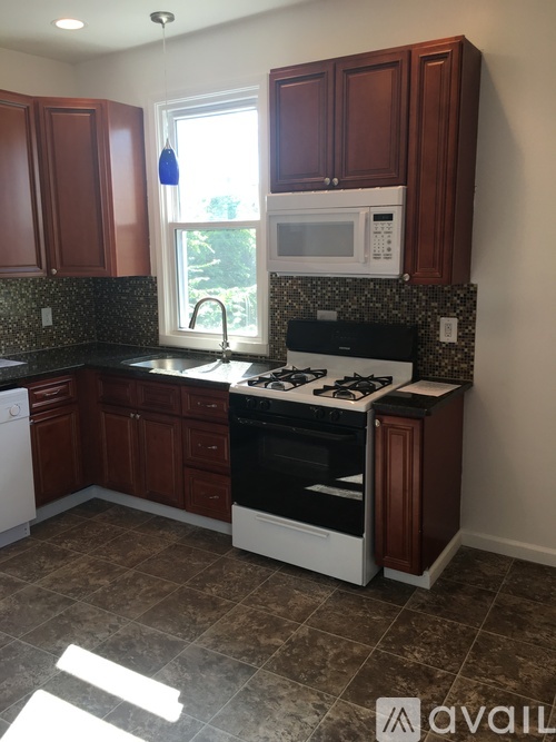 A kitchen with brown cabinets and a white microwave above the stove.