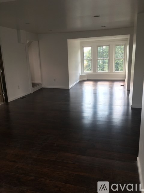 A spacious room with wooden floors and a large window.