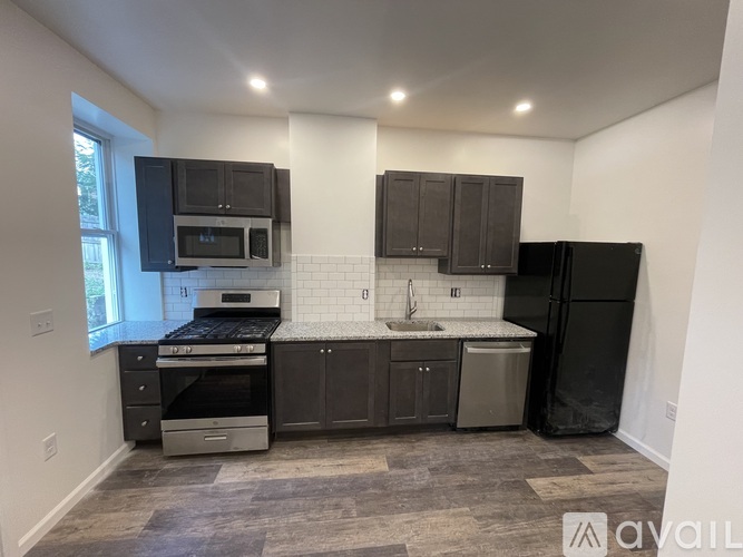 A kitchen with black cabinets and a white tiled backsplash.
