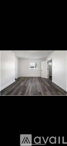 A room with wooden flooring and white walls.
