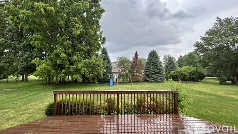 A wooden deck overlooks a grassy area with trees.