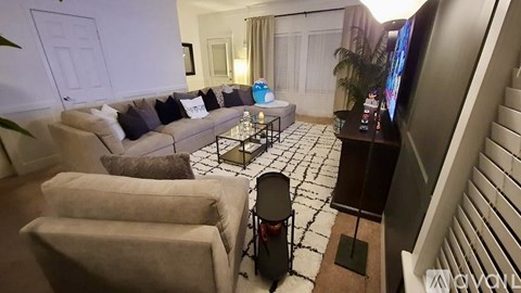 A living room with a couch, chairs, and a television.