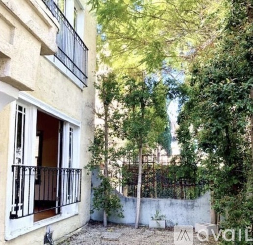 A balcony with a black railing is on the ground floor of a building.