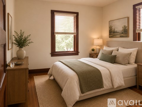 A bedroom with a large bed and a window with blinds.