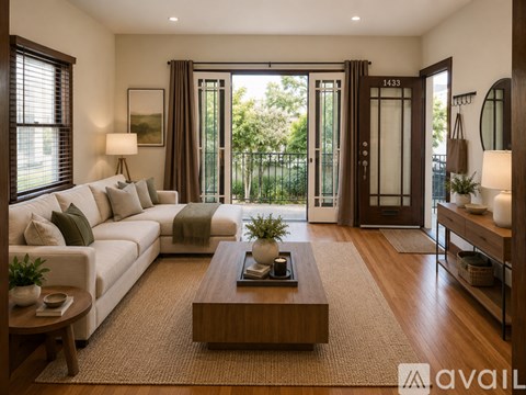 A living room with a white sofa, a wooden coffee table, and a large window with curtains.