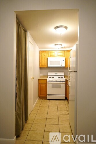 A kitchen with a white stove and oven, wooden cabinets, and a tiled floor.