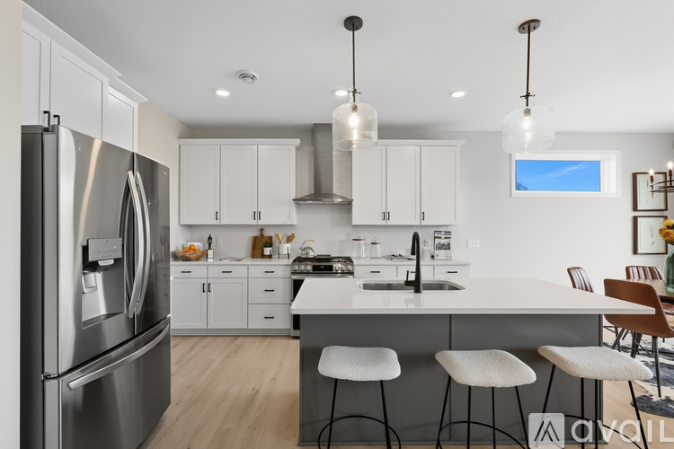 A modern kitchen with white cabinets and a stainless steel refrigerator.
