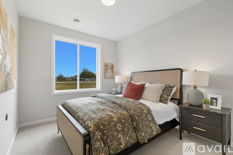 A bedroom with a large bed and a window overlooking a green landscape.