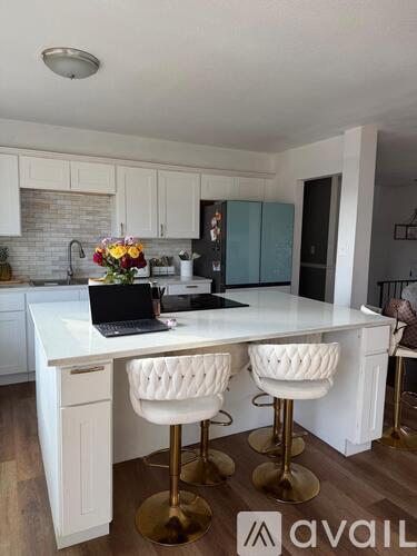 A kitchen with a white countertop and bar stools.