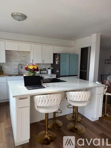 A kitchen with a white countertop and bar stools.
