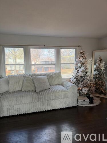 A white couch with a Christmas tree beside it in a living room.