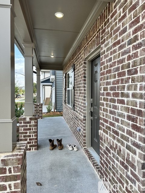 A pair of shoes are on the porch of a brick house.