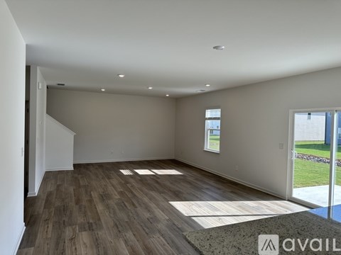 A spacious room with wooden flooring and a large window.