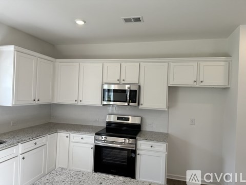 A kitchen with white cabinets and appliances.