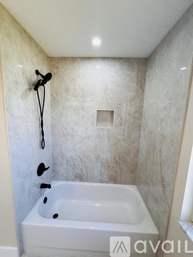 A white bathtub with a shower head and hand held shower in a bathroom.