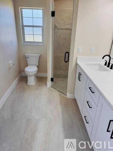 A bathroom with a toilet, sink, and a window.