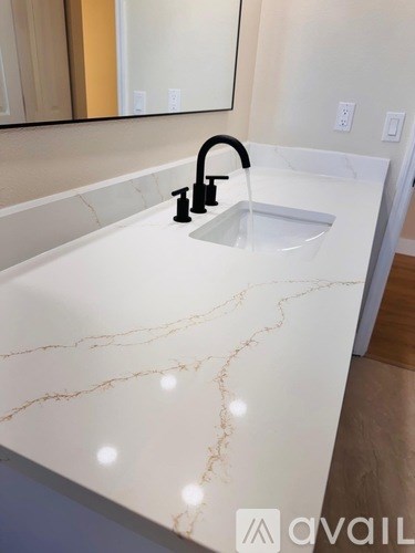 A bathroom sink with a marble countertop and a black faucet.