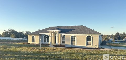A house with a grey roof and beige walls is available for sale.