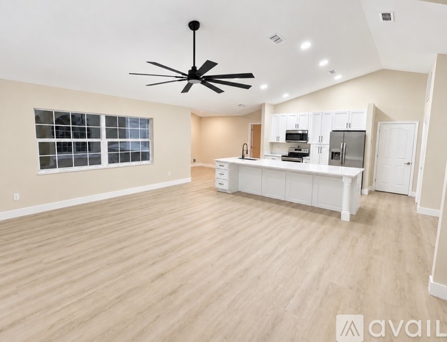 A spacious kitchen with white cabinets and a ceiling fan.