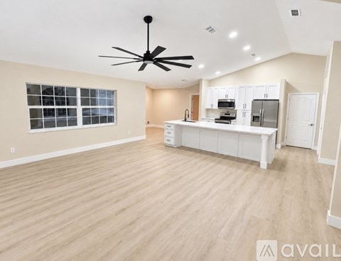 A spacious kitchen with white cabinets and a ceiling fan.