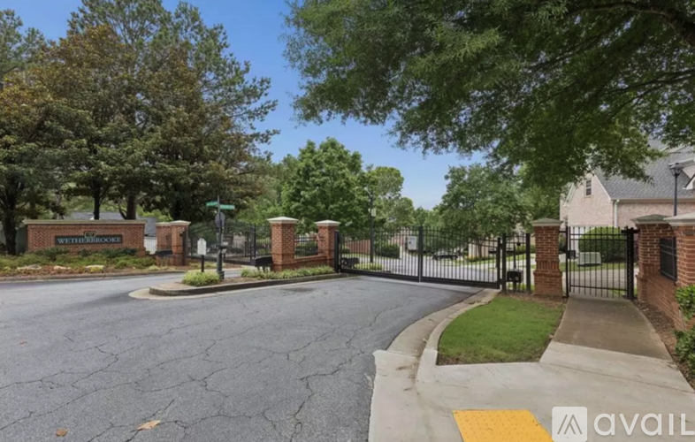 A street view of a gated community entrance with a sign that reads "AVAILABLE".