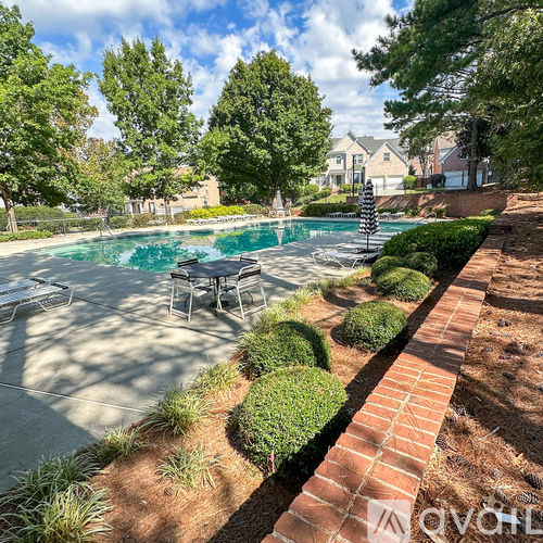A pool surrounded by a brick border and greenery.