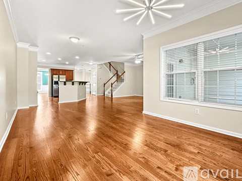 A spacious room with wooden floors and a staircase leading to another level.