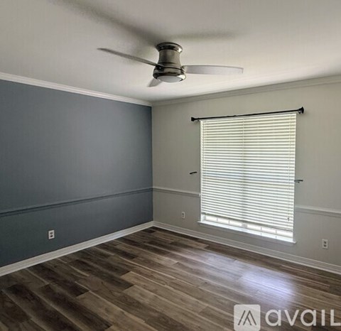 A room with a ceiling fan and a window with blinds.