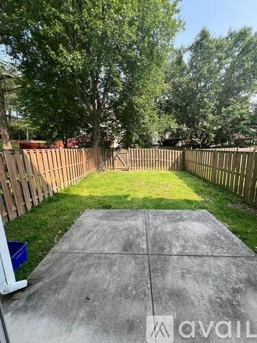 A backyard with a concrete slab and a wooden fence.