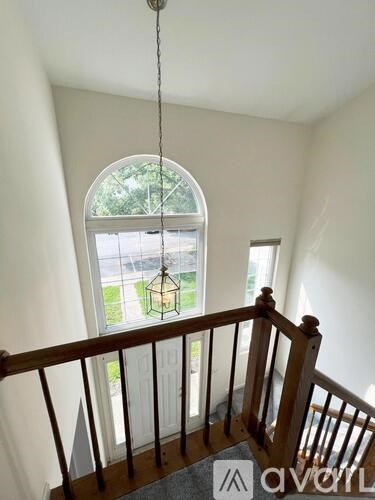 A wooden staircase with a hanging light fixture and a window in the background.