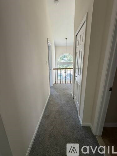A hallway with a carpeted floor and white walls.
