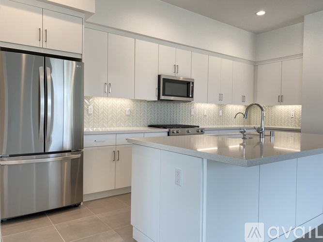 A kitchen with white cabinets and a stainless steel refrigerator.