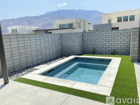 A pool surrounded by a concrete wall and grass.