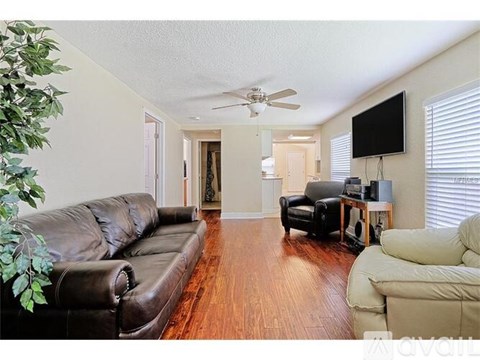 A living room with a brown leather couch and a television on the wall.